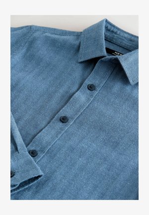 Mėlynas zigzago rašto marškinis su mygtukų apykakle, su juodomis mygtukais ir tekstūruotu audiniu.