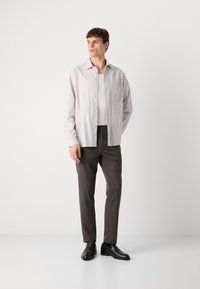 Striped button-up shirt in light purple and white, paired with dark brown trousers and black loafers, featuring a chest pocket and long sleeves.