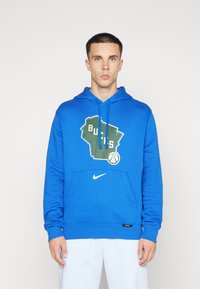 Modrá mikina s klokankou, s kresbou štátu Wisconsin, textom "BUCKS" a logom Nike na leme. Mäkkučká textúra látky.