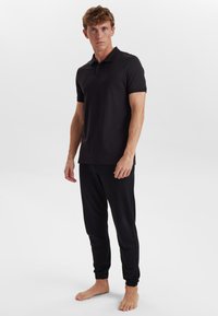 Svart pikétröja med ribbad krage, korta ärmar och slim fit, kombinerad med svarta avsmalnande joggers med elastiska mudd.