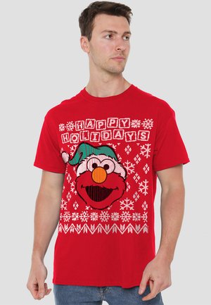 Red cotton t-shirt featuring a graphic of Elmo with a green holiday hat, text "HAPPY HOLIDAYS," and snowflake patterns.