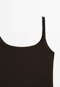Detailní záběr na tmavě hnědý texturovaný top bez rukávů s tenkými ramínky na světlém pozadí.