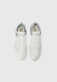 Hvite lær sneakers med teksturert design, med et blåmønstret krave, perforerte detaljer og hvite snørebånd.