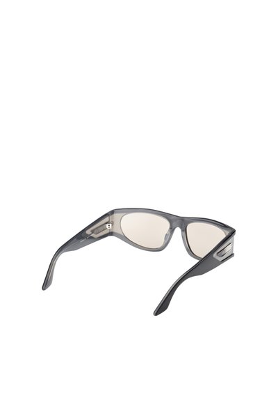 Lunettes de soleil en plastique gris au design épuré, avec des montures courbées, des verres teintés et des accents métalliques sur les côtés.