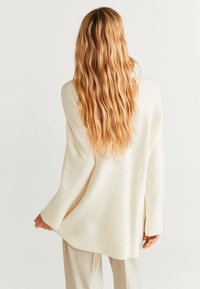 Cremefarbenes Oversized-Pullover mit gerippten Säumen und Abschluss, aus weichem Material gefertigt. Verfügt über eine lockere Passform und seitliche Schlitze für mehr Bewegungsfreiheit.