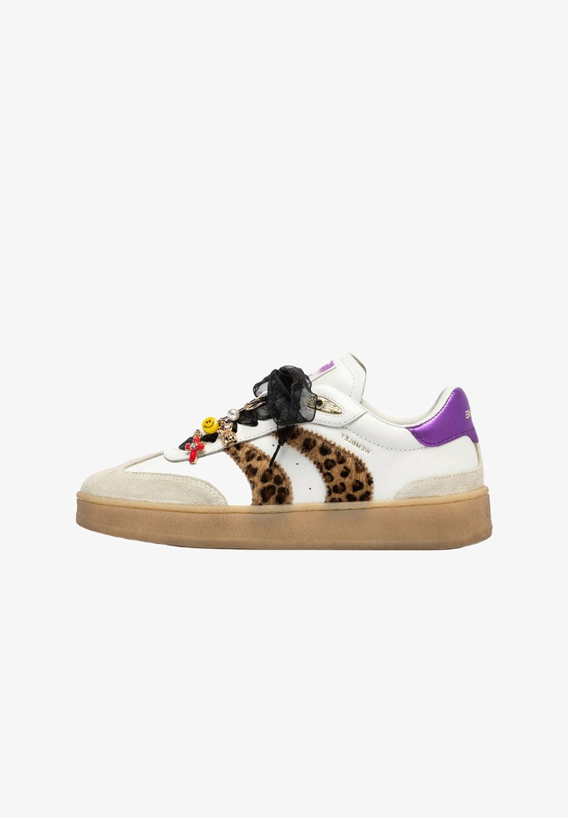 Sneaker bianco con strisce leopardate, linguetta viola, suola beige, lacci neri a nastro e dettagli decorativi tra cui una faccina sorridente e una croce.