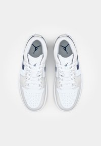 Bele čevlje za prosti čas iz usnja z mornarsko modrimi detajli, perforiranim sprednjim delom in teksturirano srednjo plastjo, ki nosijo Jumpman logotip na ježku in notranji podplati.