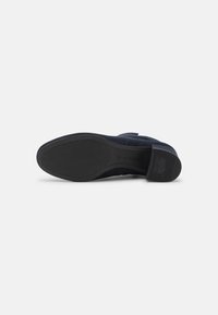 Navyblaue Wildlederschuhe mit einer strukturierten schwarzen Gummisohle. Sie verfügen über eine gepolsterte Ferse und ein glattes, abgerundetes Zehendesign.