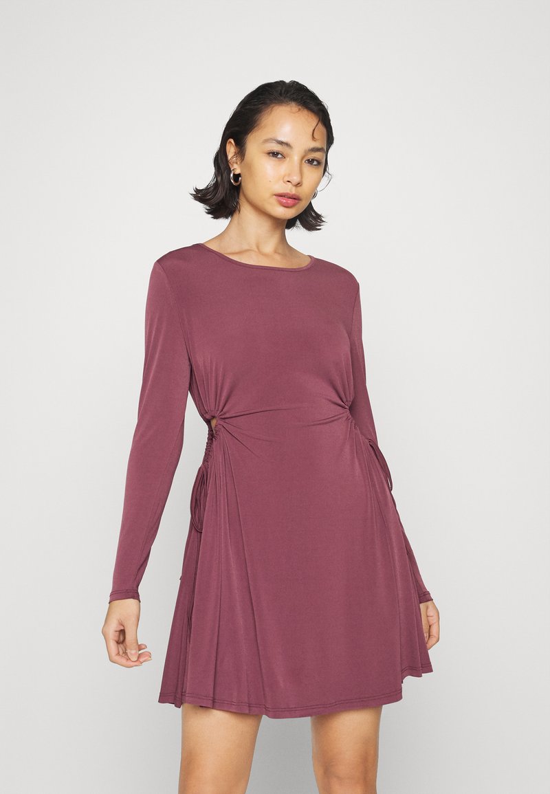 Vestido de manga longa, na cor borgonha, feito de um tecido suave, com franzidos laterais e uma silhueta a-line relaxada. Decote redondo e sem padrões.