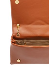 Interior de bolso de cuero marrón con un bolsillo con cremallera y herrajes dorados. Cuenta con una cadena dorada y un acabado suave y texturizado.