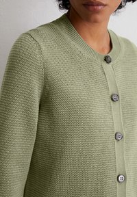Hellgrüne Strickjacke mit geripptem Kragen, durchgehender Knopfverschluss mit drei dunklen Knöpfen und einer strukturierten offenen Maschenstruktur.