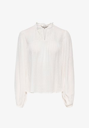 Blouse blanche à manches longues avec des pois texturés, des détails en dentelle sur le col, un léger volant et des poignets froncés.