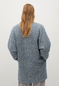 Cardigan oversize a maniche lunghe in un motivo a spina di pesce blu e bianco, realizzato in tessuto testurizzato, con vestibilità rilassata e spalle scese.