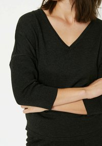 Tummanharmaa ribattua neuletta, jossa on V-mallinen kaula-aukko ja kolmannespituiset hihat. Liukastäyttöinen pinta, jossa on hieno venyvyys.