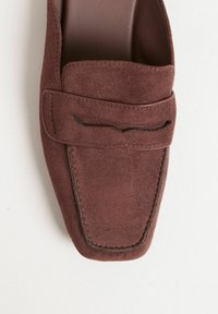 Mocassino in suede marrone con punta quadrata, caratterizzato da un accento cucito sulla parte superiore e una fodera in pelle liscia. Design con suola piatta.