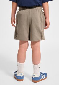 Grå bomullsshorts med snörning i midjan, sid sömmar och en avslappnad passform, parat med blå sneakers och vita ankelsockor.