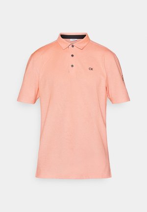 Polo de color durazno con mangas cortas, tapeta de tres botones, textura sutil y logotipo "CK" en el pecho. Dobladillo recto y cuello estándar.