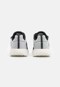 Buty sportowe z szaro-siateczkowym wierzchem, czarnymi akcentami, wyściełaną białą podeszwą środkową i teksturowaną podeszwą zewnętrzną, z centralnym szwem z tyłu.