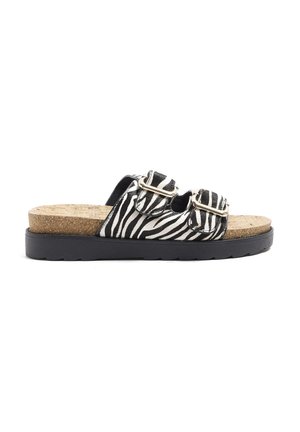 Zebra print slide sandals with two buckle straps, cork footbed, and black rubber outsole. Features textured surface and contrasting colors.