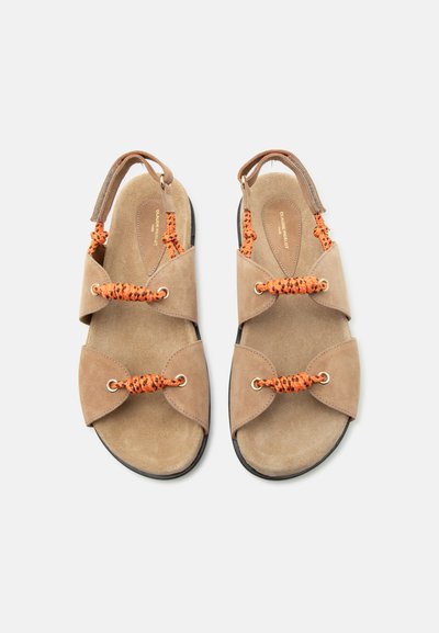 Μπεζ σανδάλια από σουέτ με μαύρα και πορτοκαλί πλεκτά λουριά, ανοιχτές μύτες και ρυθμιζόμενα πίσω λουριά σε λευκό φόντο.