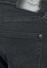 Svarta denimjeans med en slät yta, silverfärgad hårdvara och en läderetikett med "Pepe Jeans London"-logotypen på midjan.