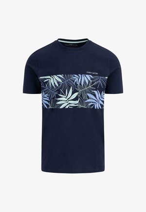 T-shirt in cotone blu marina con un motivo di foglie azzurre e verde chiaro sul petto e il nome del marchio "Fynch Hatton" stampato sopra.