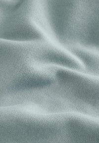 Tessuto azzurro chiaro con una texture liscia, caratterizzato da un sottile motivo a maglia e una morbida caduta, che appare leggermente stropicciato.