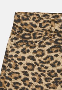Denim tkanina s leopardjim vzorom, svetlo rjave osnove in črnimi pikami. Ima visok pas, zanke za pas in subtilne šivalne detajle.