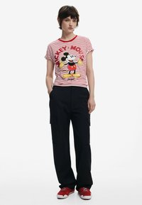 Rød og hvidstribet t-shirt med et grafisk print af Mickey Mouse, parret med sorte cargo-bukser og røde sneakers.