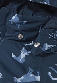 Blauer Stoff mit einem Muster aus hellblauen Füchsen, ausgestattet mit metallischen Druckknöpfen und einer glatten Textur. Das Design enthält verschiedene Tierformen.