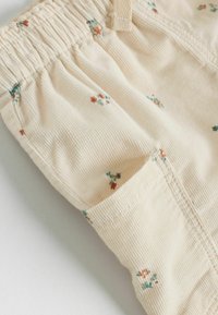 Beiga kordflorshorts med ett samlat midjeband, prydda med små blommönster i orange och blått. Inkluderar en sidficka.