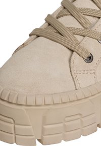 Baskets en suède beige avec une finition texturée, épaisse semelle plateforme et orteil arrondi. Dotées de lacets tressés beige et d'œillets en métal.