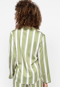 Groen en wit gestreept shirt met lange mouwen, een kraag en een zakdetail, gemaakt van een gladde stof met een licht glanzende textuur.