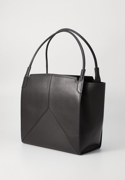 Sort læder tote bag med to runde håndtag, en struktureret form og geometrisk syning detalje på frontpanelet.