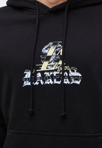 Μαύρο φούτερ με κουκούλα με vintage λογότυπο Los Angeles Lakers που περιλαμβάνει μεγάλο "L" και φθαρμένο λευκό κείμενο στο στήθος.