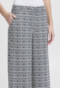 Pantalons blancs et navy à motif géométrique, dotés d'une taille haute et de poches latérales, fabriqués en tissu doux.