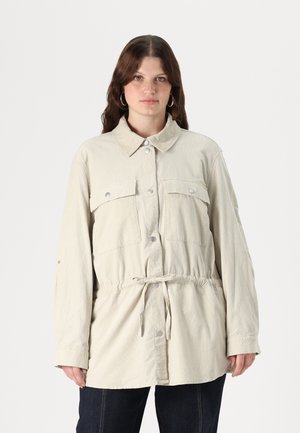 Light beige jacket with a button-up front, two chest pockets, and a drawstring waist. Features long sleeves and a classic collared neck.