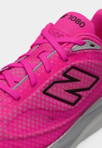 Chaussure de course New Balance rose vif avec texture en maille, lacets roses, semelle grise et numéro de modèle "1080" imprimé sur la languette.