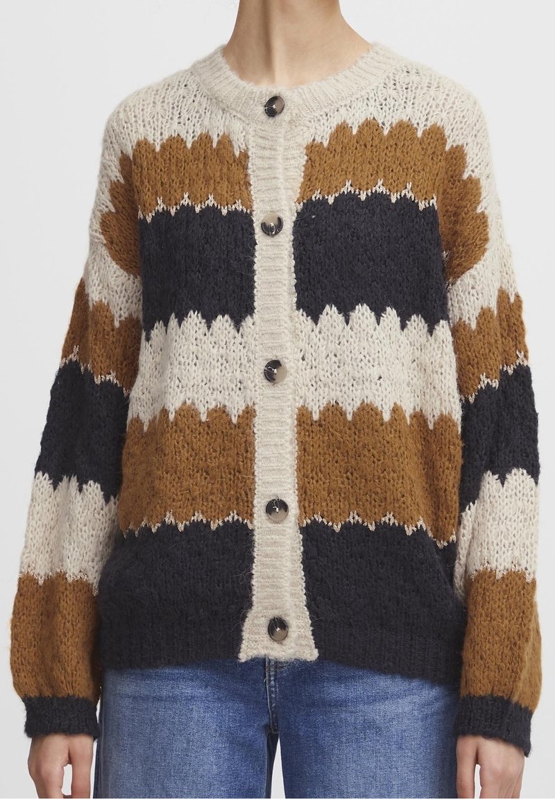 Paksu neulejakku, jossa on voikaan, ruskeaa ja laivastonsinisiä raitoja. Pyöreä kaula-aukko, kuusi nappia edessä ja resorit hihansuissa. Rakenteinen kangas.