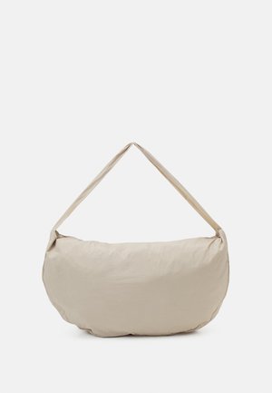 Borsa a spalla beige con superficie liscia e leggermente testurizzata, forma ovale e una tracolla ampia e piatta per un trasporto confortevole.