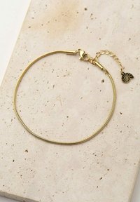 Pulsera chapada en oro con un diseño de cadena suave y flexible, cierre tipo langosta, y un pequeño colgante con un patrón en espiral.
