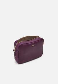 Trousse de maquillage en cuir violet avec une fermeture éclair dorée, en forme rectangulaire, texture lisse et logo à l'avant. Ouverture par fermeture éclair sur le dessus.