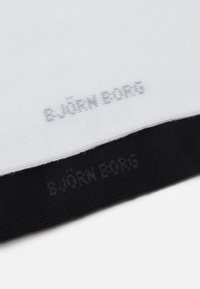 Calze in bianco e nero con una texture liscia. Presentano il marchio "BJÖRN BORG" in grigio sia sulle sezioni bianche che nere.