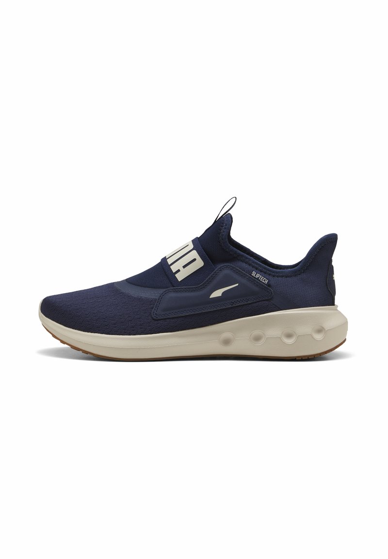 Scarpa sportiva blu navy con tomaia in tessuto testurizzato, design slip-on, suola beige a contrasto e accenti di logo minimalisti.