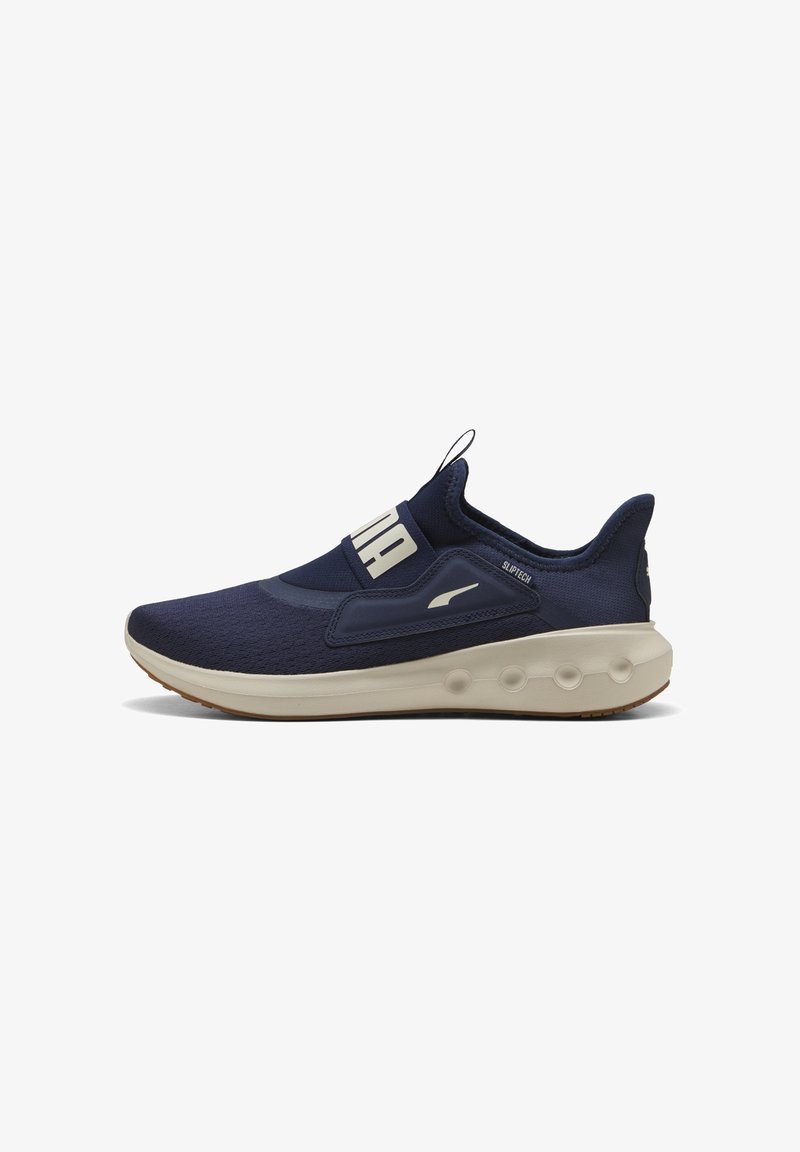 Scarpa sportiva blu navy con tomaia in tessuto testurizzato, design slip-on, suola beige a contrasto e accenti di logo minimalisti.