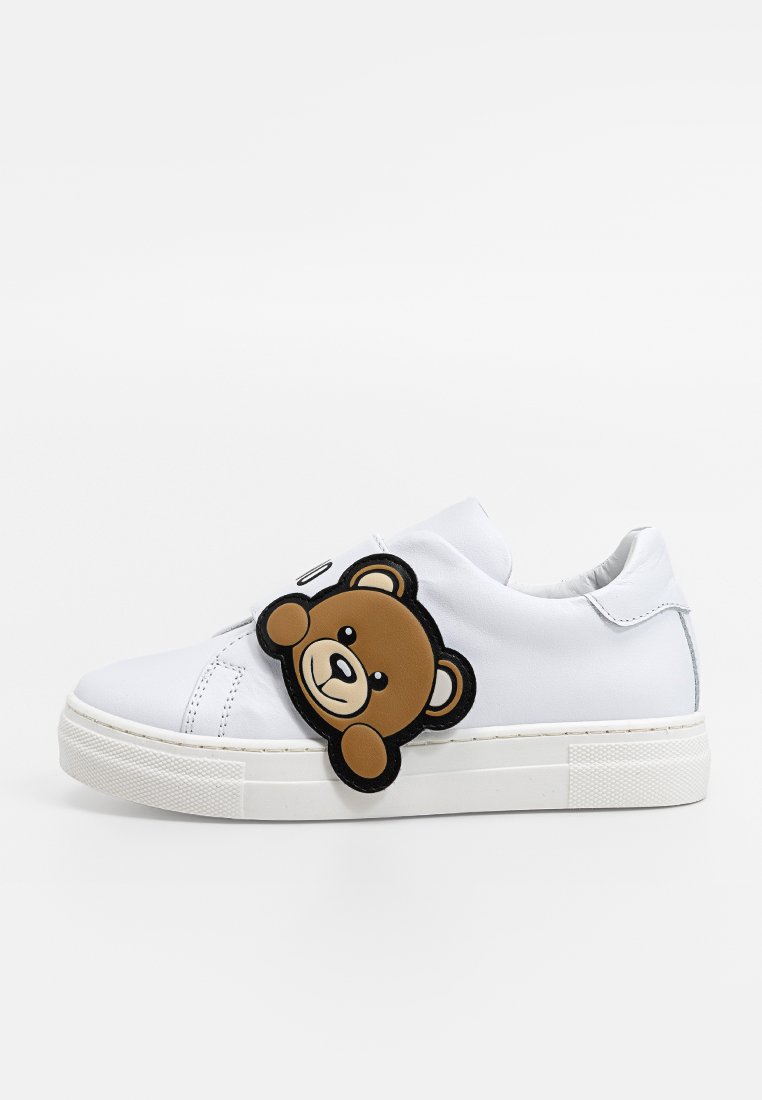 Sneaker bianca con una texture liscia, caratterizzata da una grande toppa con la faccia di un orso bruno sul lato e una suola in gomma bianca.