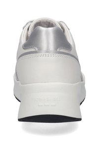 Białe sneakersy z gładką skórzaną cholewką, metalicznymi srebrnymi akcentami przy pięcie oraz teksturowaną czarną gumową podeszwą.