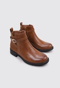 Botines de cuero marrón con acabado suave, cremallera lateral, detalle de correa, tacón bajo y diseño de punta redondeada. Suela exterior de goma negra.