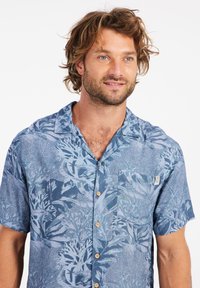 Korte mouwen shirt in lichtblauw met een bladpatroon, knopenlijst aan de voorkant en een opgestikte zak. Gemaakt van ademende stof, met een ontspannen kraag.