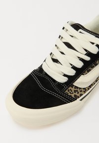 Sorte ruskinds sneakers med dyreprint på siden, cremefarvede snørebånd og hvid sål. Har kontrastsyet og en glat læderlogo accent.